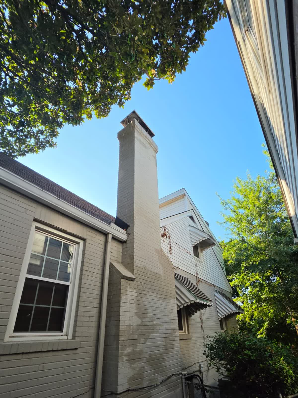 The full chimney before any work, from the side yard, painted over patched masonry