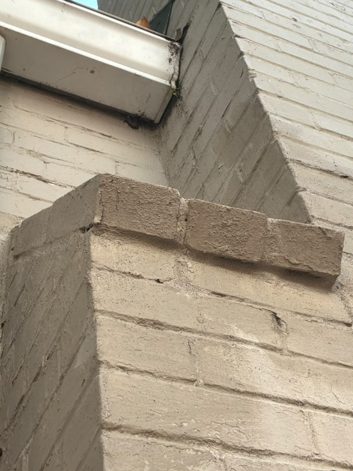 Stepped brick shoulder below the gutter line with cracked and open mortar joints