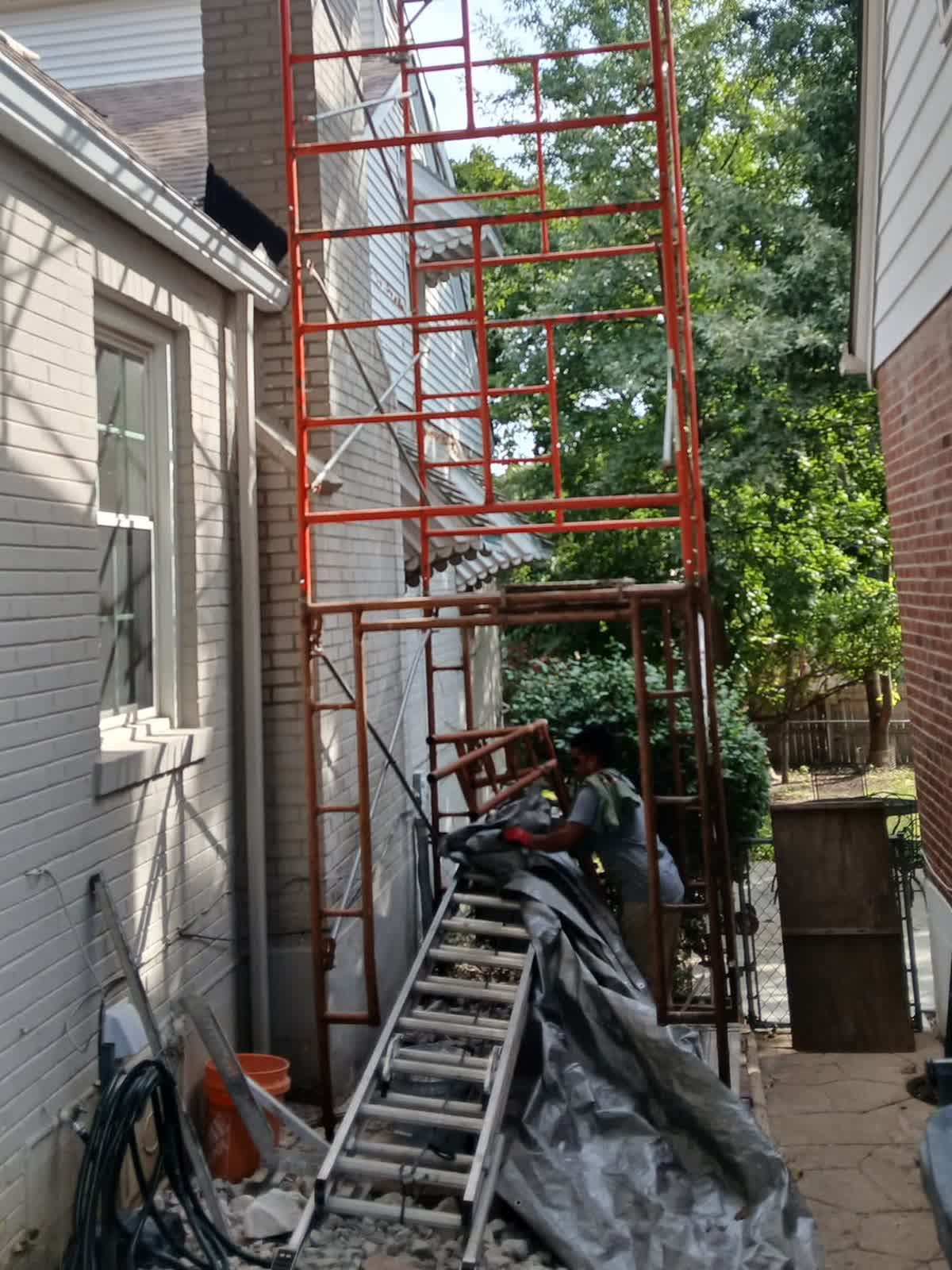 Scaffolding built the full height of the chimney in the narrow side yard between two houses