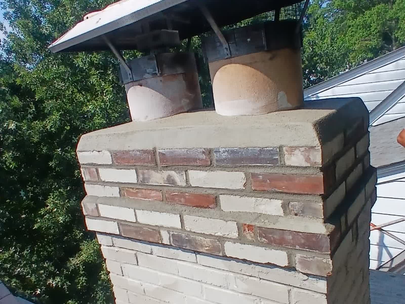 The new chimney crown hanging out past the rebuilt brickwork, with the cap back on above it
