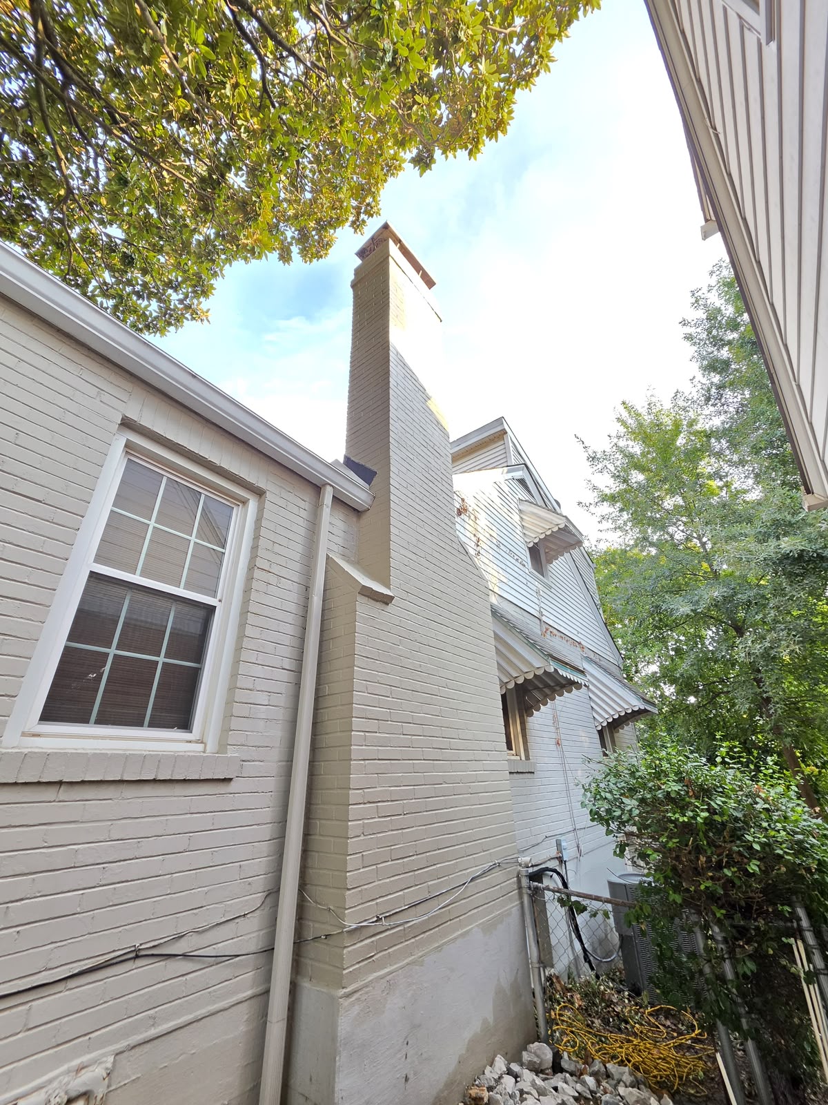 Completed chimney seen from the side yard, painted in one even colour from roofline to crown