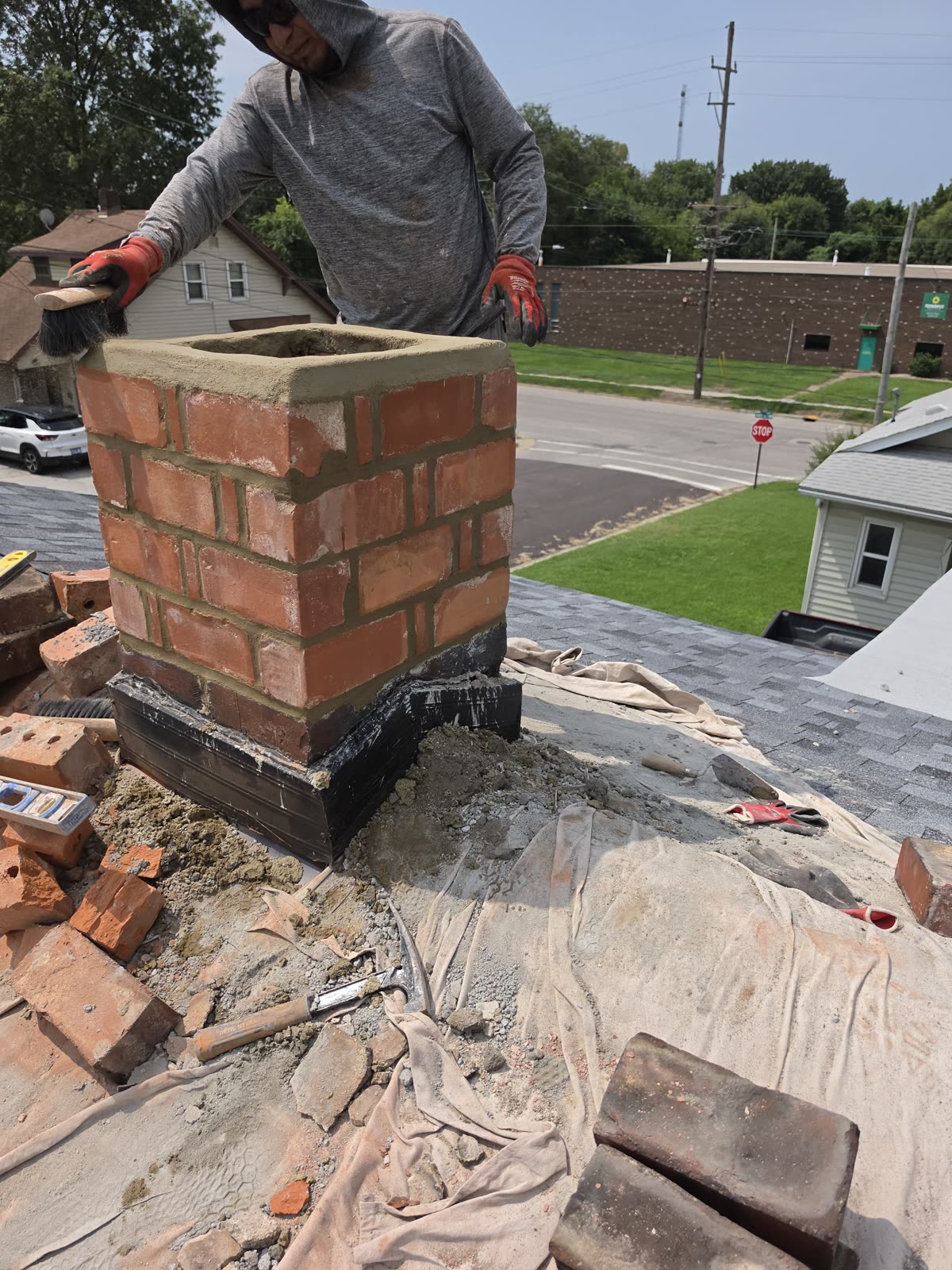 Mason brushing the fresh mortar at the rebuilt chimney termination