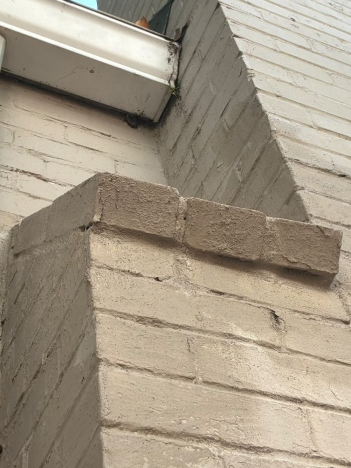 Stepped brick shoulder below the gutter with cracked open joints